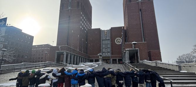 en gruppe mennesker som står på en steingangvei med bygninger i bakgrunnen en gruppe mennesker som står på en steingangvei med bygninger i bakgrunnen