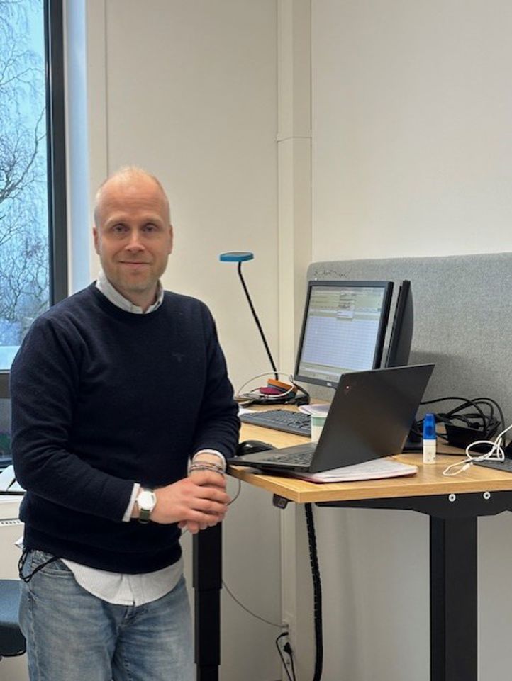 en person som står foran et skrivebord med en bærbar PC på