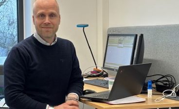 en person som står foran et skrivebord med en bærbar PC på en person som står foran et skrivebord med en bærbar PC på