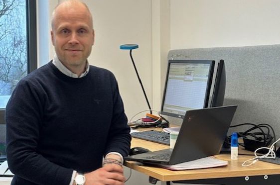 en person som står foran et skrivebord med en bærbar PC på en person som står foran et skrivebord med en bærbar PC på