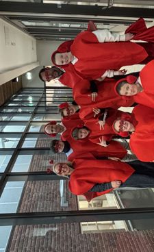 En gruppe mennesker i røde og hvite uniformer står foran en bygning