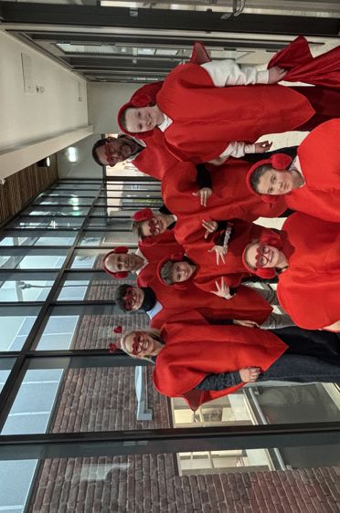 En gruppe mennesker i røde og hvite uniformer står foran en bygning