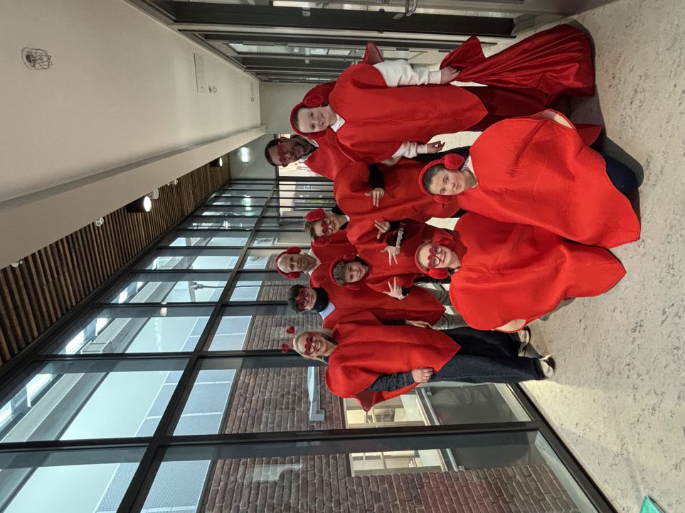 En gruppe mennesker i røde og hvite uniformer står foran en bygning