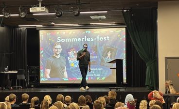 en person på en scene med en stor skjerm foran en folkemengde