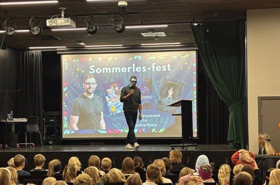 en person på en scene med en stor skjerm foran en folkemengde