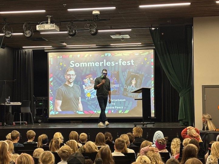 en person på en scene med en stor skjerm foran en folkemengde